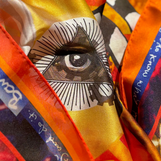 A close up showing the all seeing eye detail on the fire and water coloured fine silk scarf, Ingenuity by Anna Acciarini.