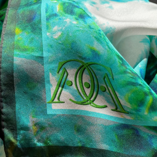 The Serenity silk scarf showing a corner detail with green signature on green pattrn background.