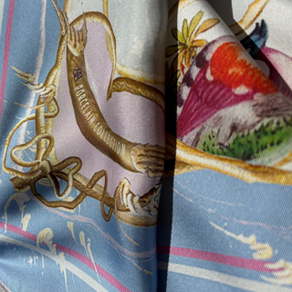 Detail of the Chelsea Lovebirds light blue, gold and colourful birds patterned scarf, freely after an antique Chelsea Porcelain Plate showing the Porcelain Collection inscription and Anna Acciarini logo.