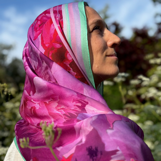 Model wearing the long Love Peony silk scarf as a pink head scarf with mint green edge.