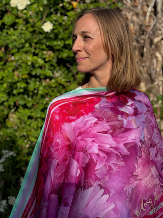 Model in early evening light wrapped in pink silk scarf. The long Love Peony scarf glows in pink and magenta hues.