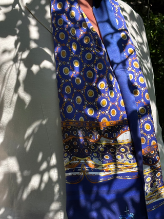Detail of Northumbria blue satin silk scarf showing the goldand white spot pattern in dappled sunlight
