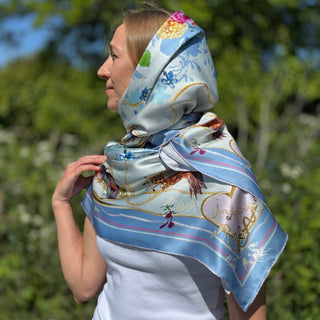 Elegant female model in white blouse wearing Chelsea Lovebirds scarf as a poetic headscarf, sunlight catching silk sheen