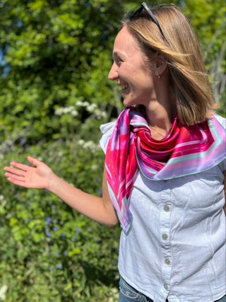 Model shown in white top with the Love Peony Silk Scarf styled in a side knot, capturing its romantic, elegant character.