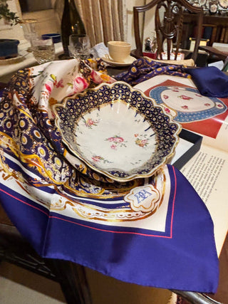 The Northumbria Silk Scarf paired with the original 18th-century Chelsea-Derby porcelain plate that inspired the design.