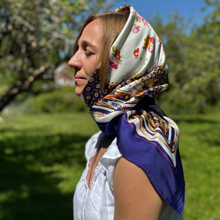 Left profile of model wearing The Northumbria scarf as a head wrap, capturing the regal shimmer of silk in motion.