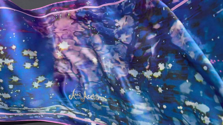 Silk scarf flowing to show ripples, sparkle, and Anna Acciarini script in gold calligraphy