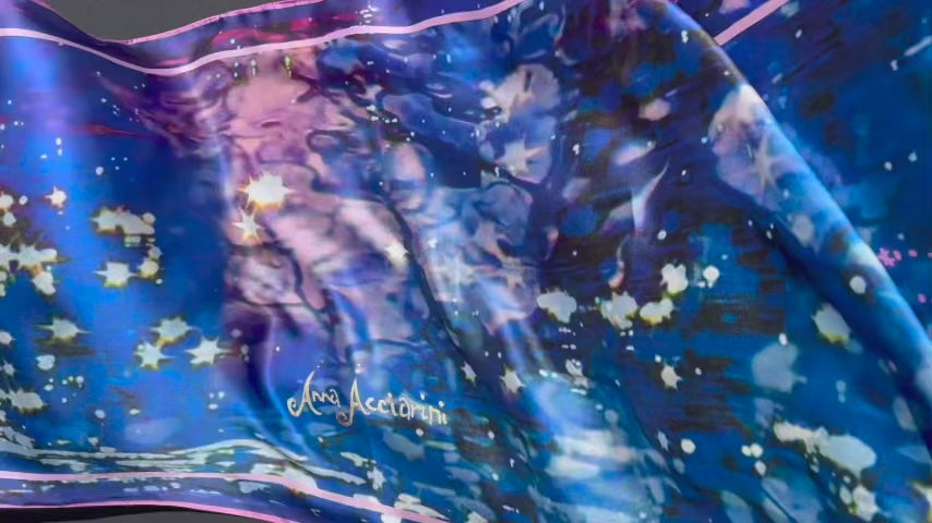 Silk scarf flowing to show ripples, sparkle, and Anna Acciarini script in gold calligraphy