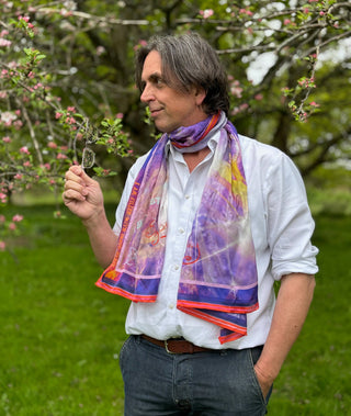 silk scarf in purple with gold and white sparkles, red border, and ‘Synchronicity’ and ‘Serendipity’ in bold script worn around neck